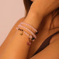 Woman wearing a stack of pink beaded bracelets/Rose Quartz Amulet Bracelet on a plain background