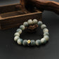 Tibetan Bracelet with Six-Word Mantra with a gold charm on a dark surface with wooden background