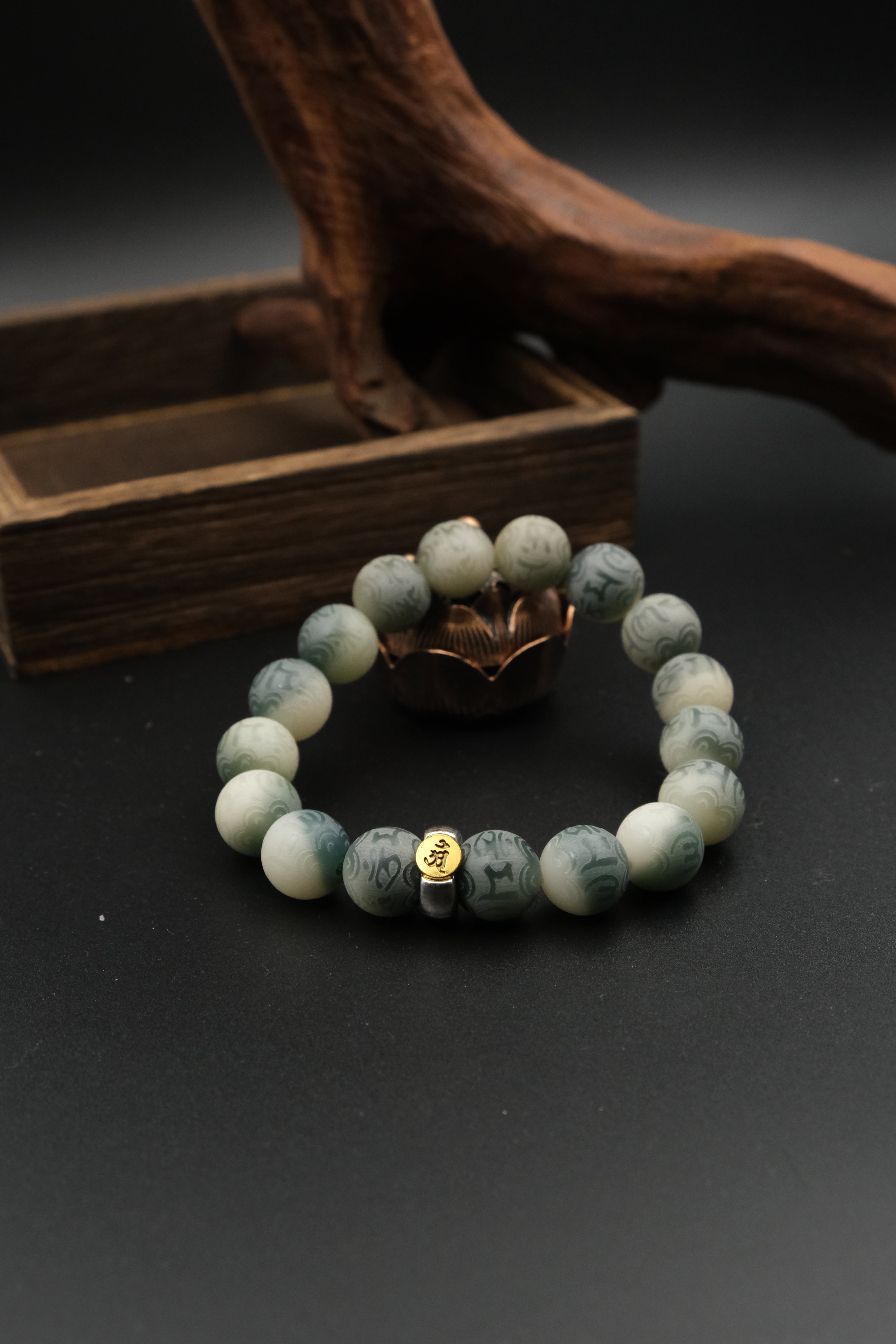 Tibetan Bracelet with Six-Word Mantra with a gold charm on a dark surface with wooden background