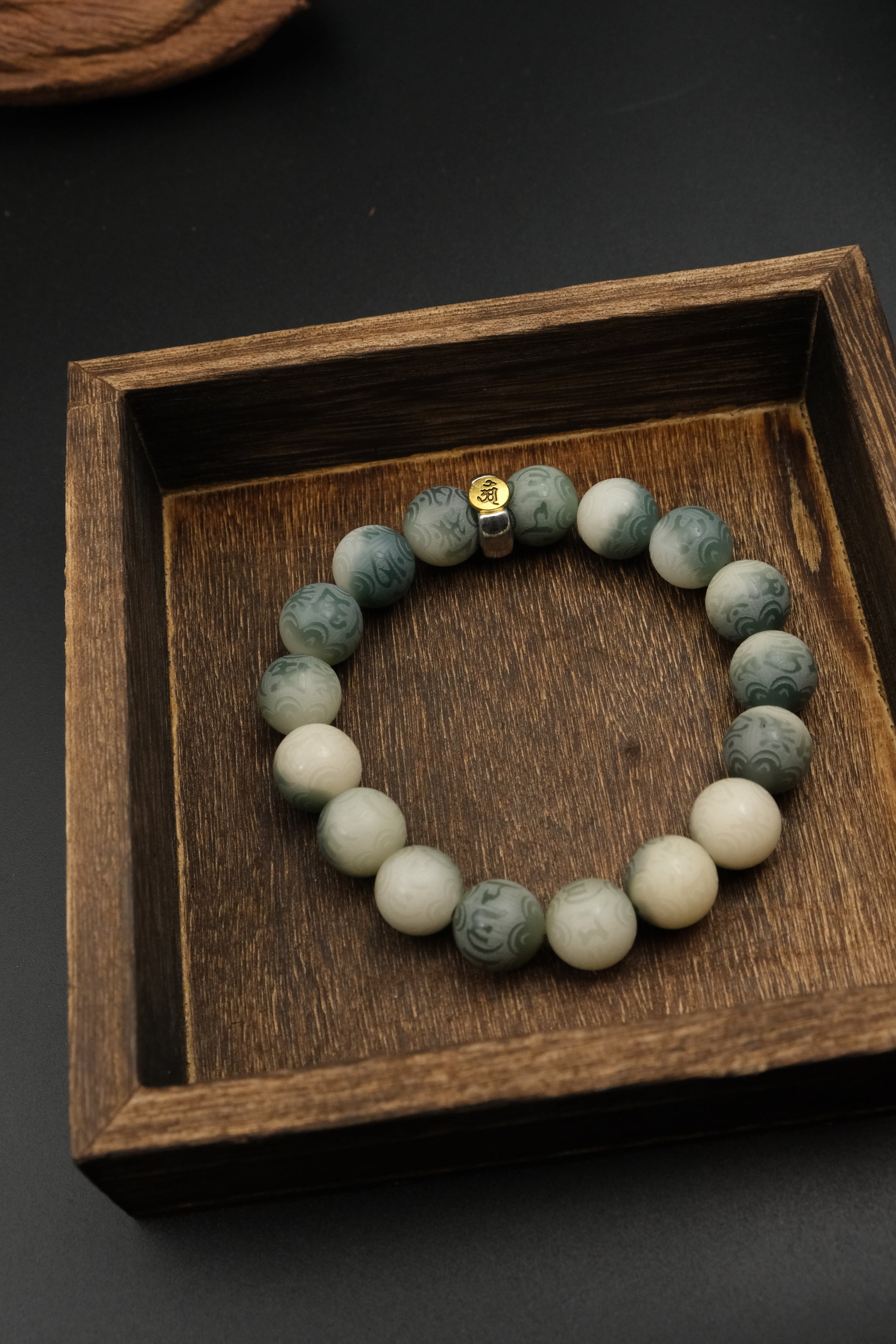 Tibetan Bracelet with Six-Word Mantra on a wooden tray with a dark background