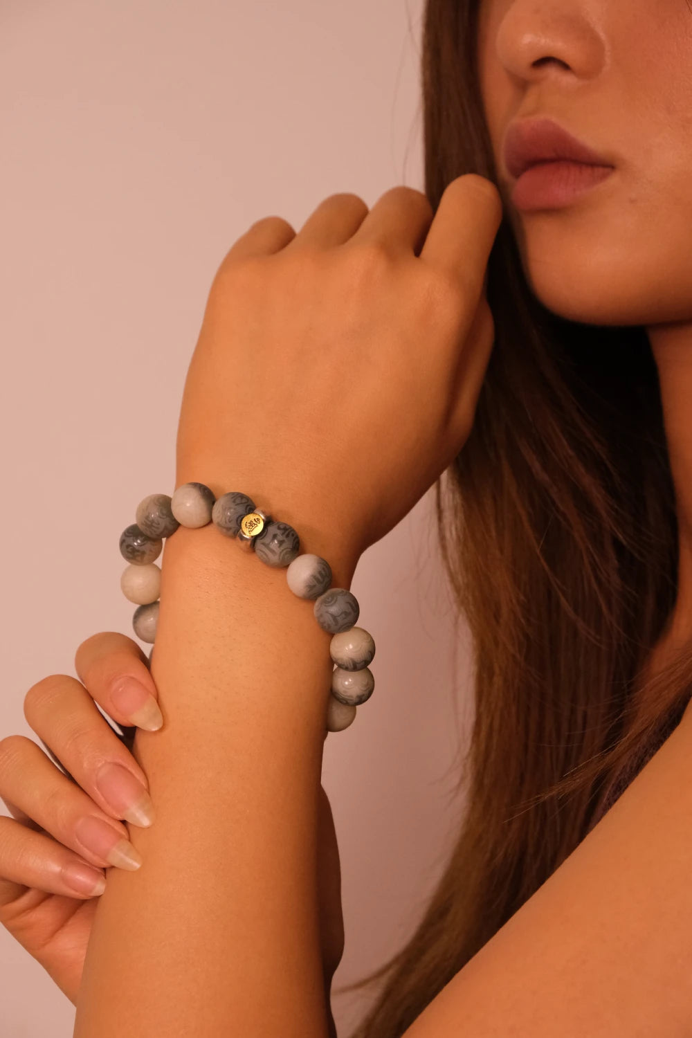 Woman wearing a Inner Balance & Protection – Tibetan Six-Word Mantra Bracelet on a pink background