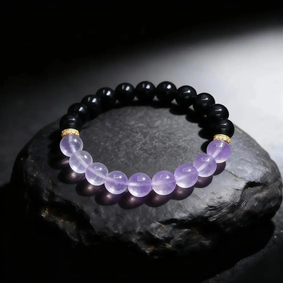 Bracelet with purple and black beads on a dark stone surface
