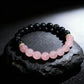 Bracelet with Black Obsidian and Rose Quartz beads on a dark stone surface