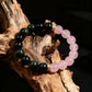 Two beaded bracelets, one black and one pink, on a wooden surface.