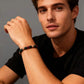 A male model wearing the multi-colored bead bracelet on his wrist against a grey background.