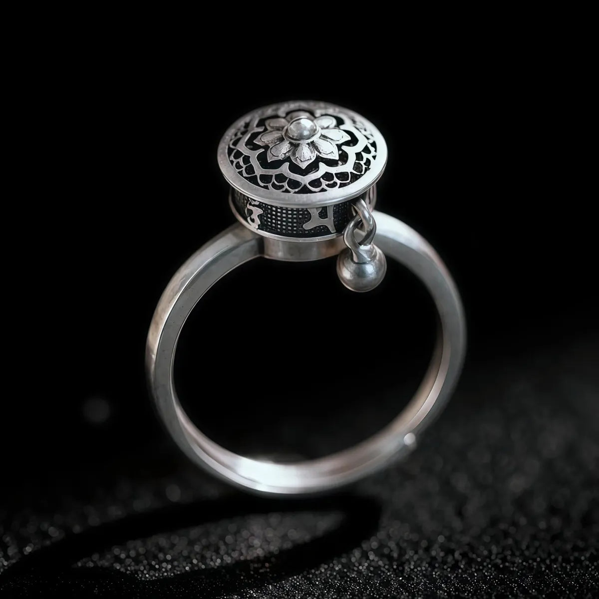 Manifest Flow Tibetan silver Lotus Mantra spinner ring on black background, handcrafted with intricate lotus and mantra design, symbolic energy jewelry for intention and mindfulness.
