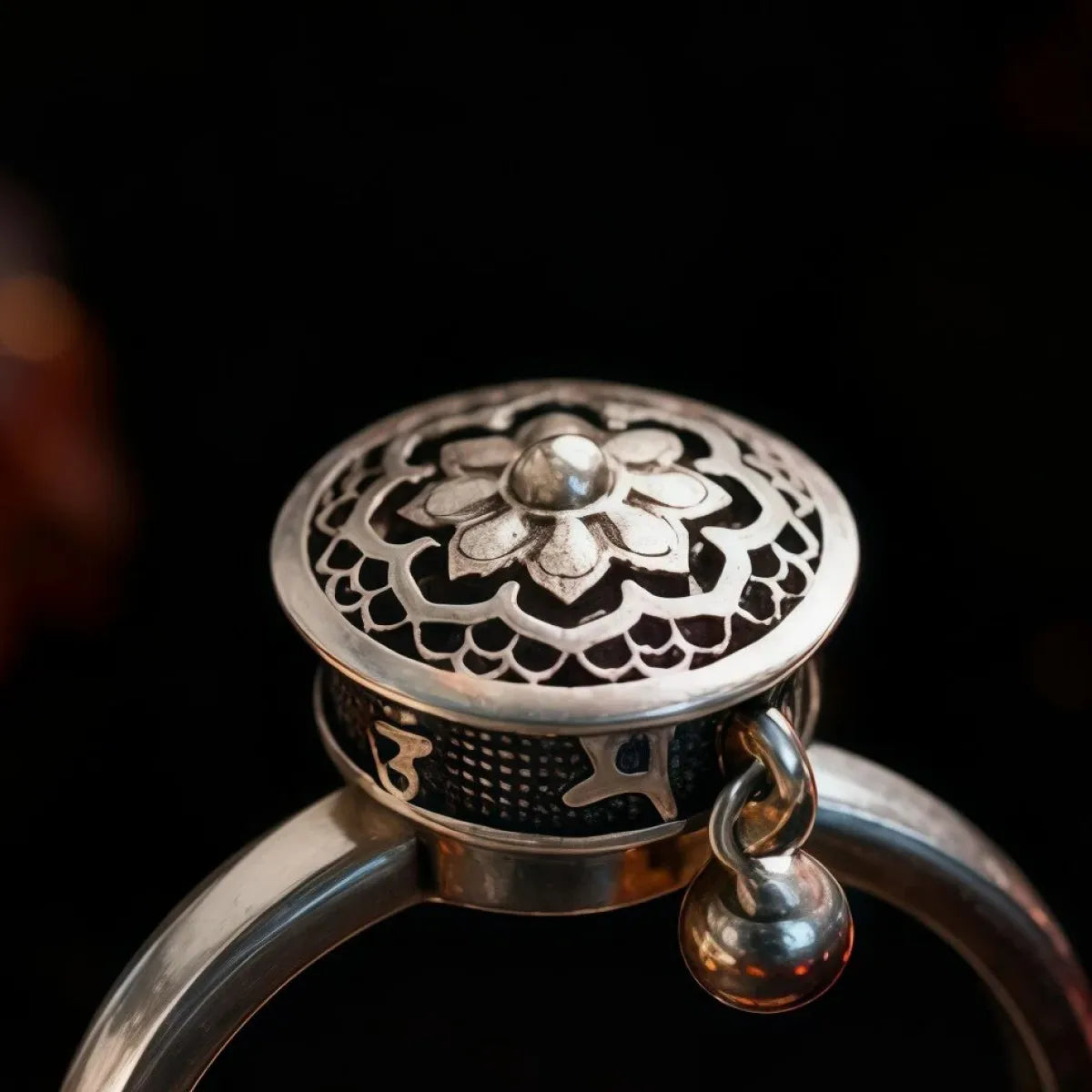 Silver ring with intricate design on a black background
