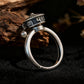 Silver ring with decorative top on a dark background