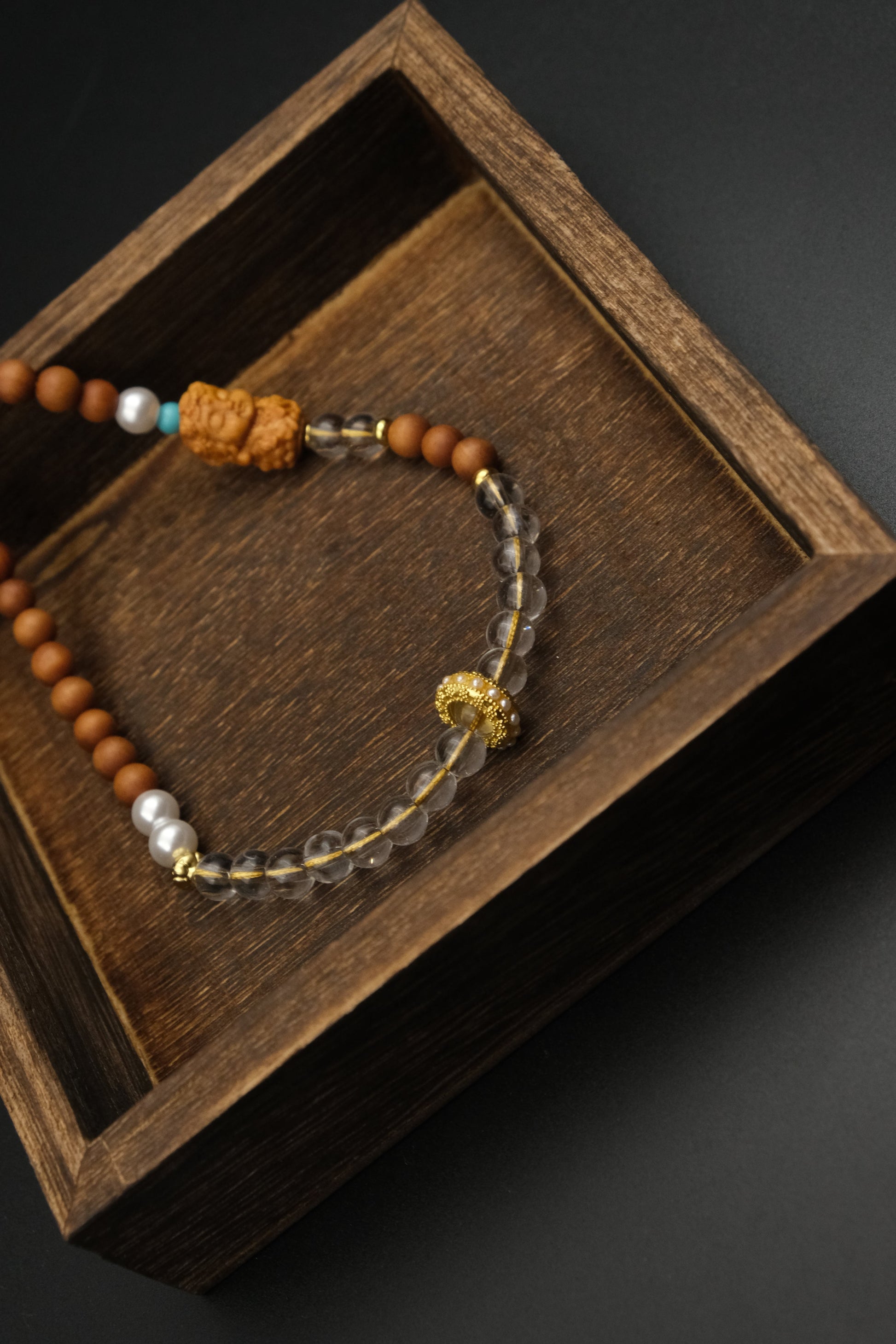 Calm & Positivity – Sandalwood Buddha Charm on a wooden box with a dark background