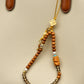 Beaded keychain with decorative elements hanging from a beige handbag.