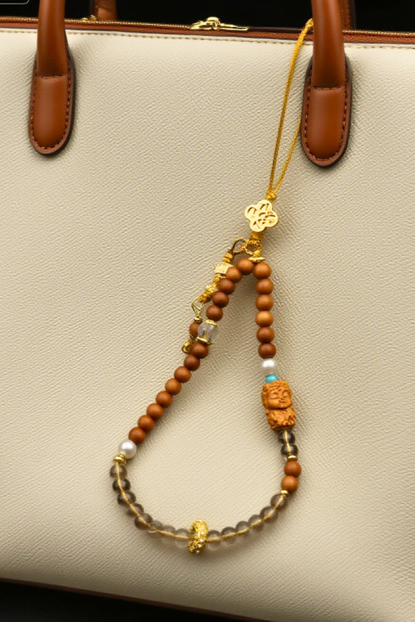 Beaded keychain with decorative elements hanging from a beige handbag.