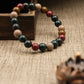 Multicolored beaded Aromatherapy bracelet on a textured surface with a wooden box and pine cone.