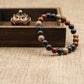 Multicolored beaded Aromatherapy bracelet with five elements on a wooden stand with a textured brown background