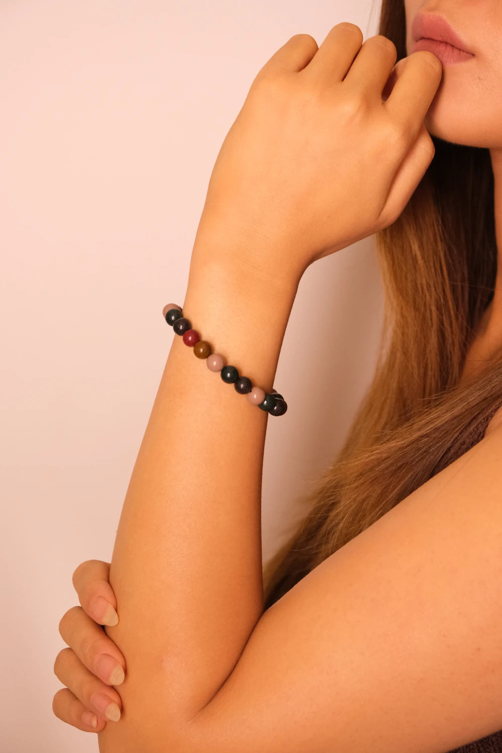 Close-up of a person wearing a Nature Five Element Aromatherapy bracelet on a plain background