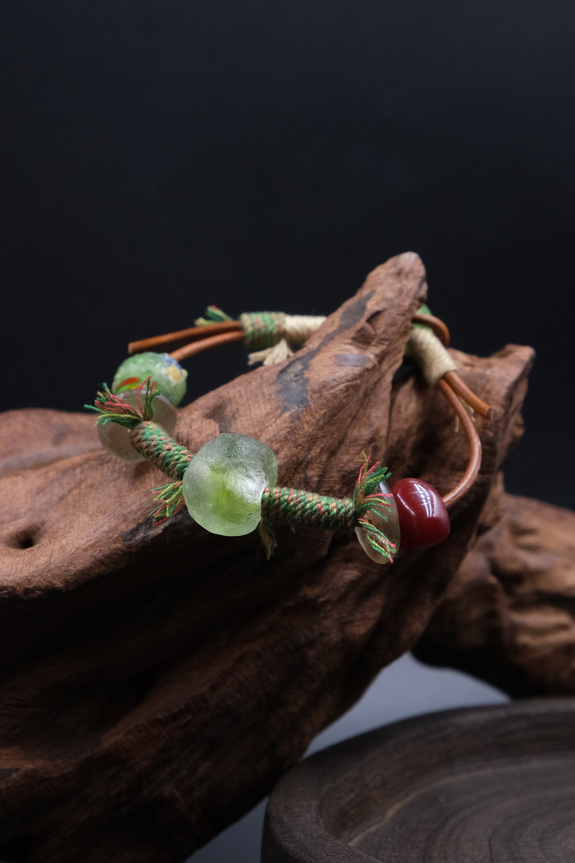 Ancient Liuli Talisman Bracelet, for Grounding & Intention, on a piece of wood against a dark background