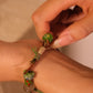 Close-up of a hand wearing a Forest Ritual Liuli Bracelet with natural elements on a neutral background