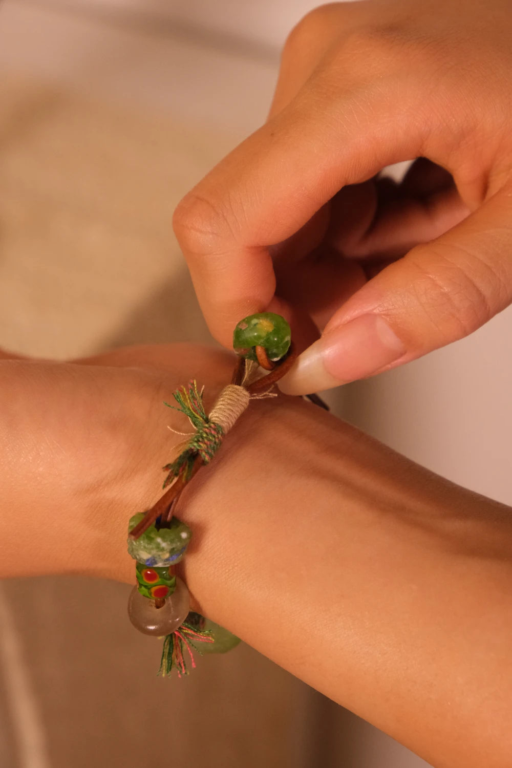 Close-up of a hand wearing a Forest Ritual Liuli Bracelet with natural elements on a neutral background