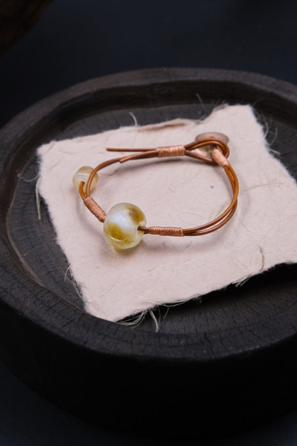 Ancient liuli bead Sun Spirit bracelet, unique design that promotes grounding and inner clarity, styled on a textured background.