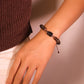 Close-up of a hand wearing Tibetan-style bracelet made of stones, wood, and liuli beads, designed for spiritual harmony on a neutral background