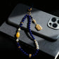 Decorative beaded phone charm on a smartphone with a dark background