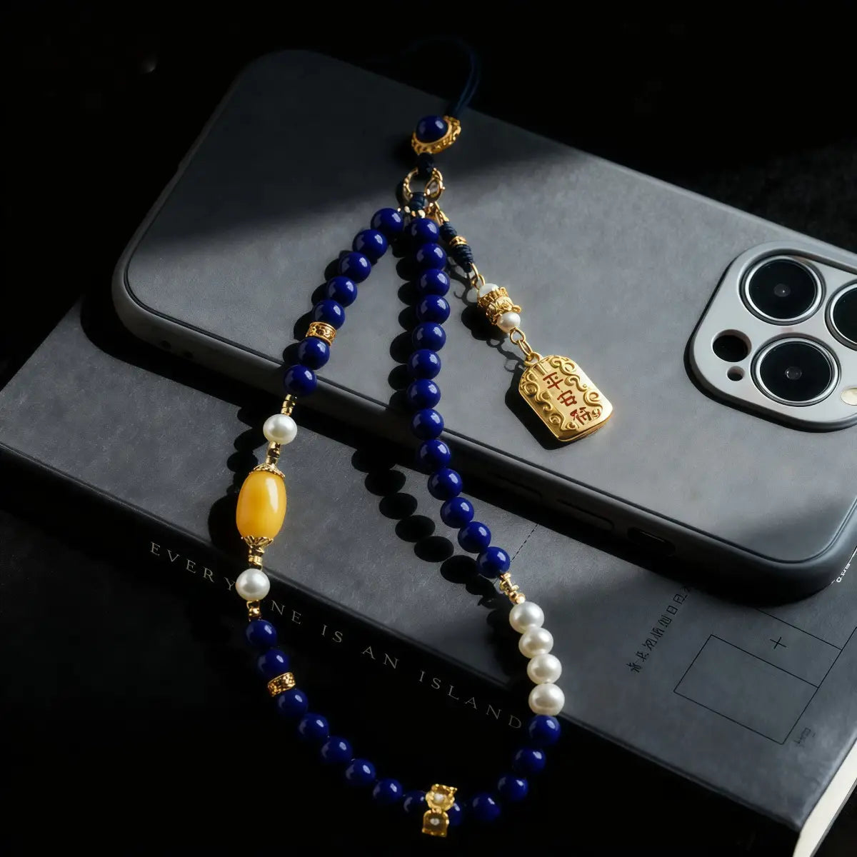 Decorative beaded phone charm on a smartphone with a dark background