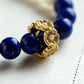 Bracelet with blue Lapis Lazuli beads and a gold clasp on a light background