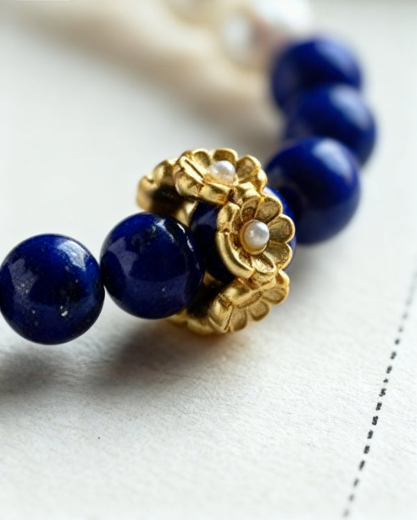 Bracelet with blue Lapis Lazuli beads and a gold clasp on a light background