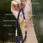 Hand holding a beaded necklace with labeled stones against a blurred natural background