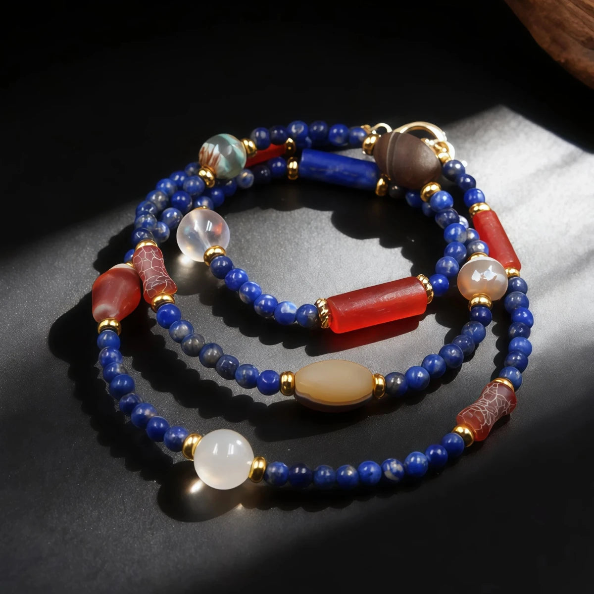 Beaded bracelet with blue, red, and gold beads on a dark surface