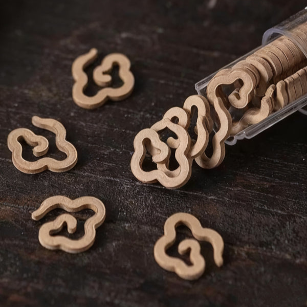Cloud - shaped incense slices, some spilled from a transparent container onto a dark wooden surface.