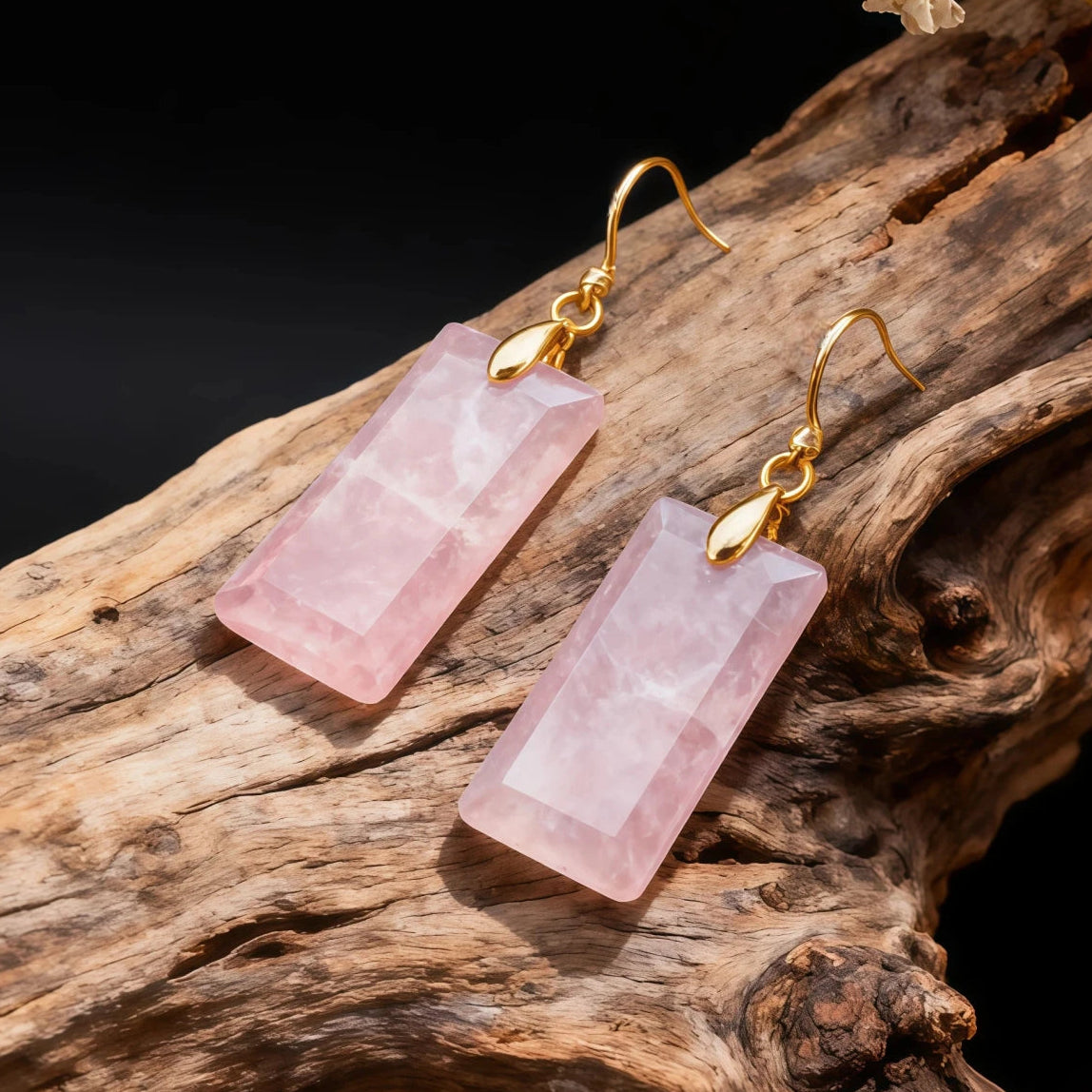 Rose quartz earrings with gold hooks on a wooden surface