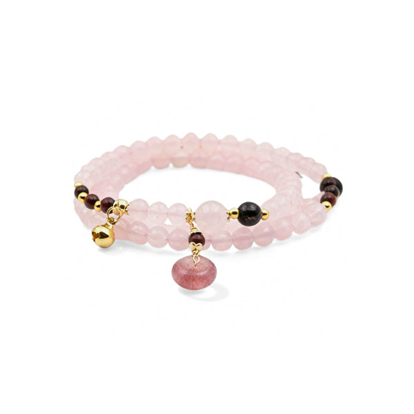 A multi-layer bracelet crafted from rose quartz beads, adorned with a golden bell charm, dark-hued beads, and a strawberry quartz pendant.