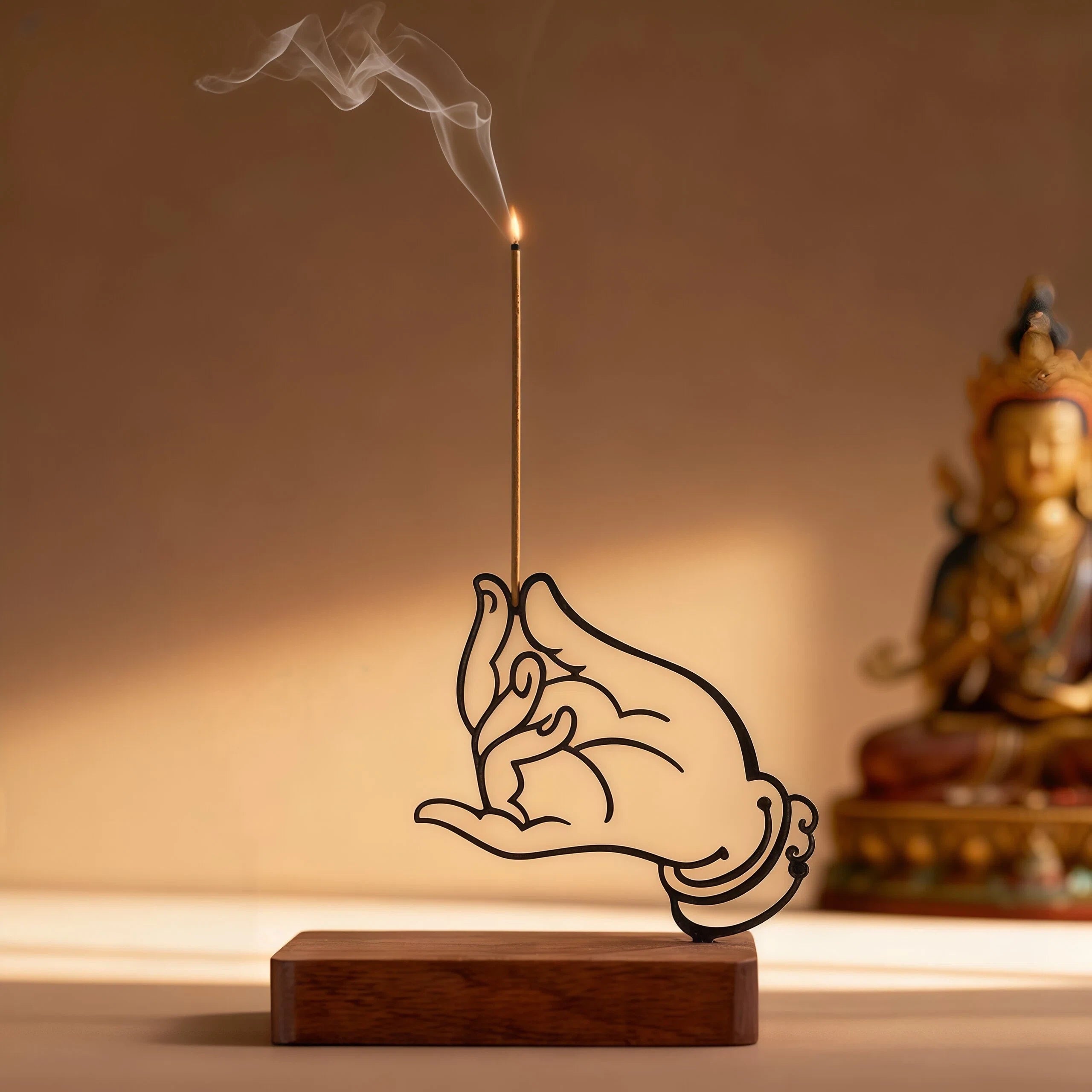 Incense stick holder shaped like a hand with a Buddha statue in the background