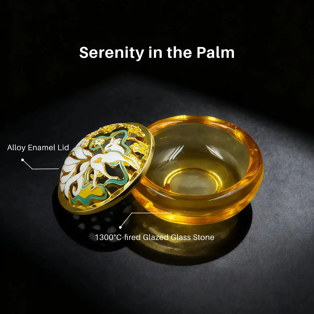 Glass container with gold lid featuring enamel design on a black background