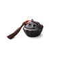 Ceramic lotus pod mini incense burner with dark glaze, lotus-shaped lid, brown tassel, and red bead, symbolizing stillness and clarity.