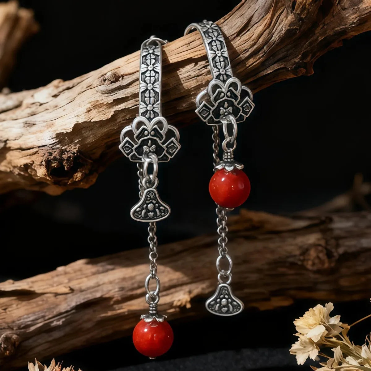 Tibetan Silver earrings with red beads on a wooden branch background