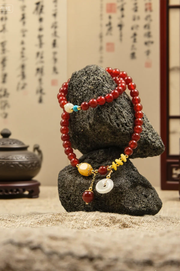 Tibetan Blessing bracelet with red and gold beads on a black stone against a dark background