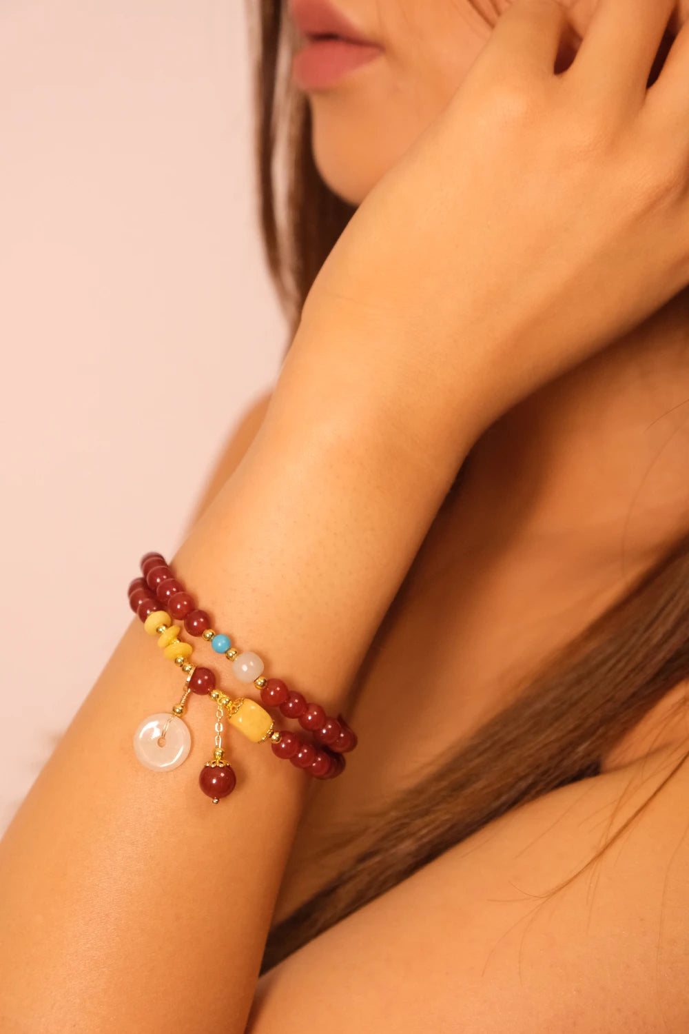 Close-up of a person's arm wearing a colorful Tibetan Blessing Bracelet on a plain background