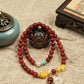Bracelet with red beads and decorative elements on a textured fabric background