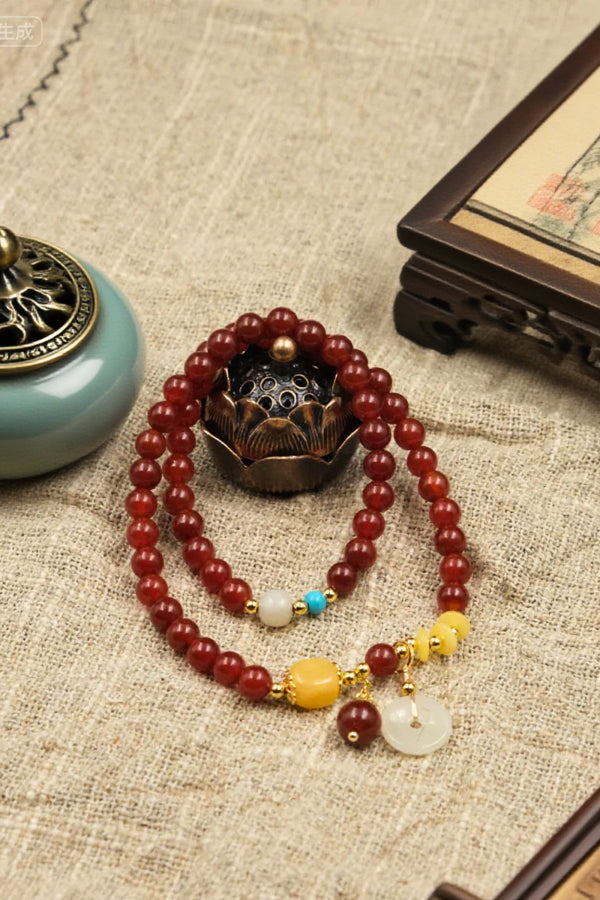Bracelet with red beads and decorative elements on a textured fabric background