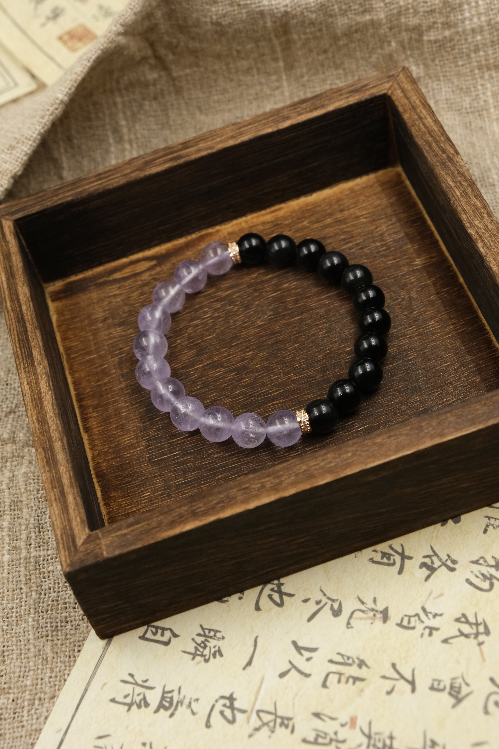 Intuition & Peace – Tibetan Dual Energy Bracelet on a wooden box with a textured fabric background