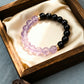 Black beaded bracelet with purple beads in a wooden box on a light blue background