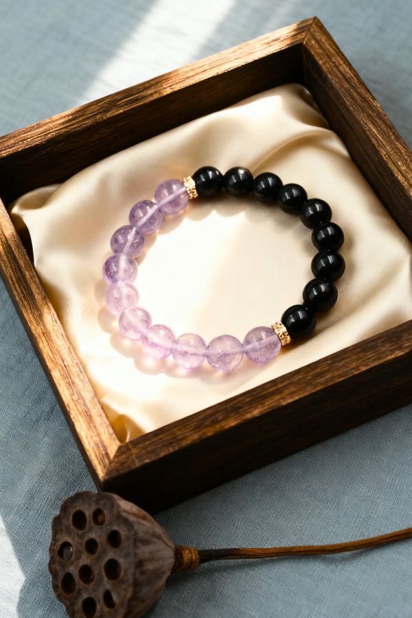 Black beaded bracelet with purple beads in a wooden box on a light blue background