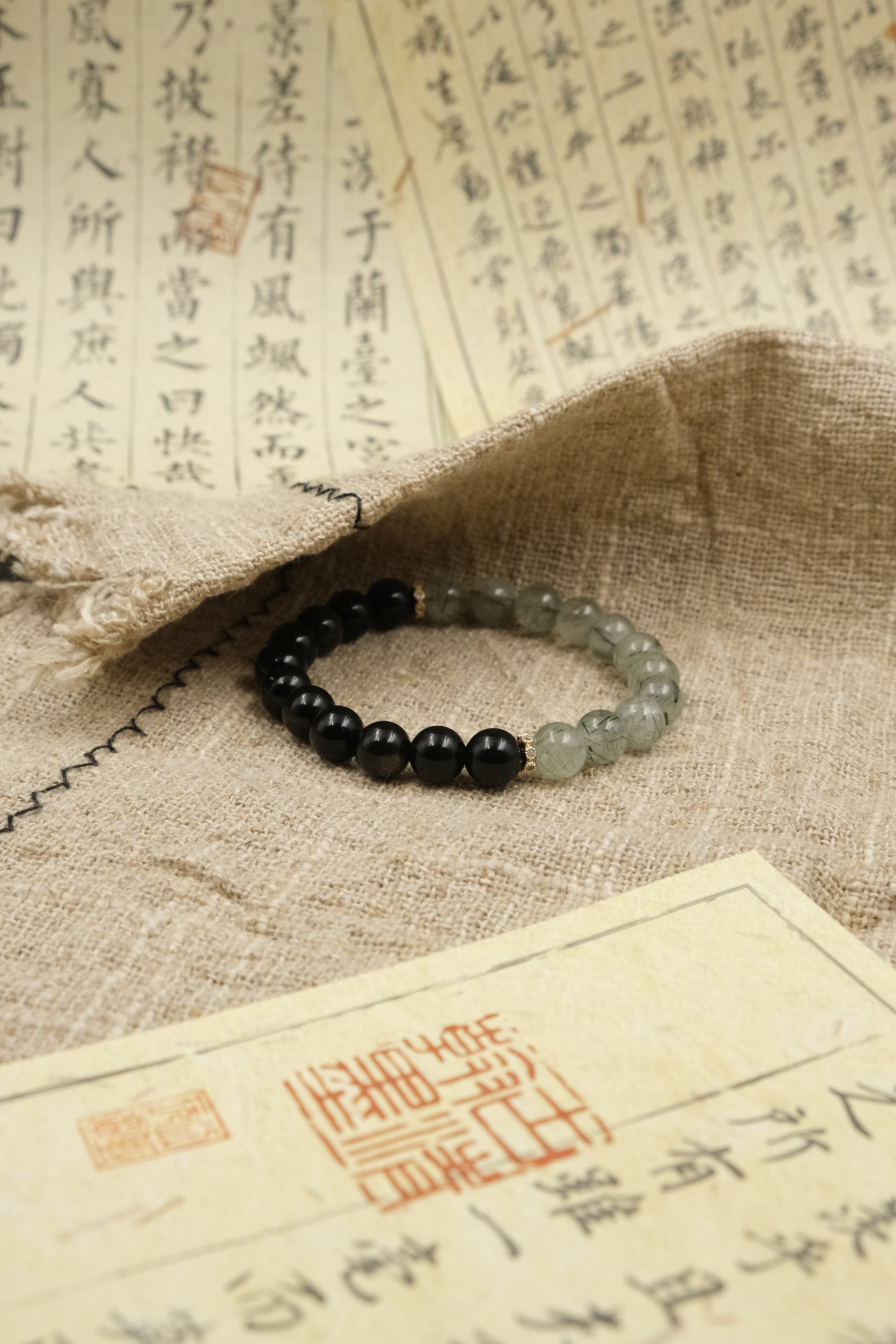 Black and green Tibetan Dual Energy beaded bracelet on a textured surface with classical Chinese text