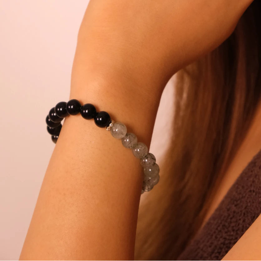 Close-up of a person wearing a Tibetan Dua _Energy beaded bracelet on a plain background
