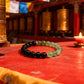 Bracelet on a red surface with prayer flags and prayer wheels in the background
