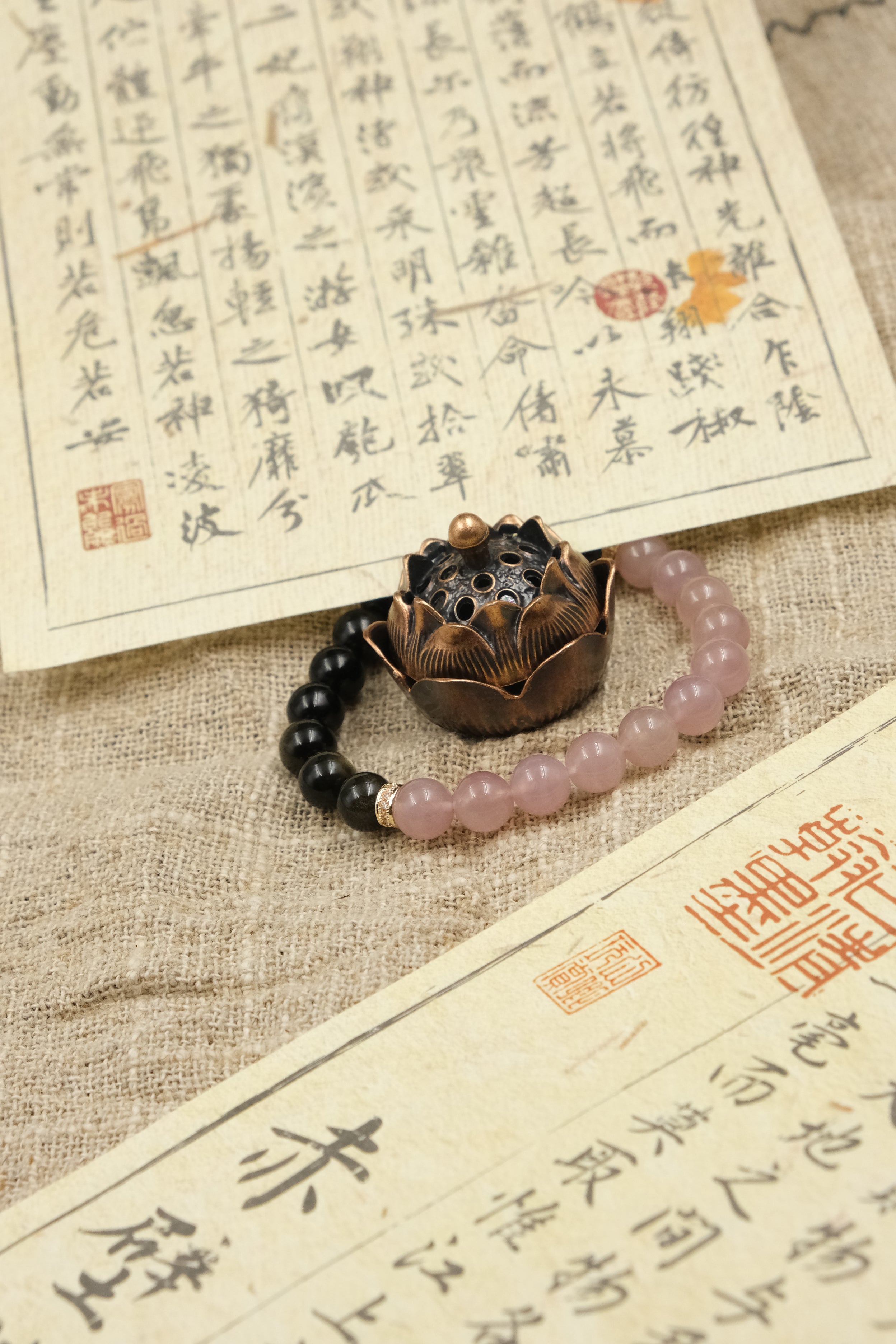 Tibetan Dual Energy Bracelet with Obsidian & Rose Quartz for Protection, Love & Social Harmony on a textured surface with calligraphy