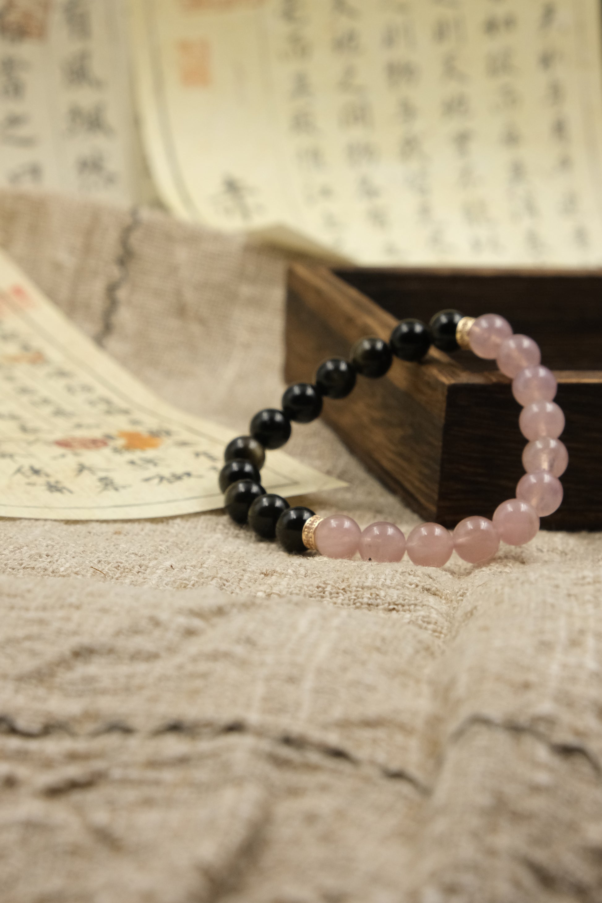 Love & Harmony Tibetan Dual Energy Bracelet with black and pink beads on a textured surface