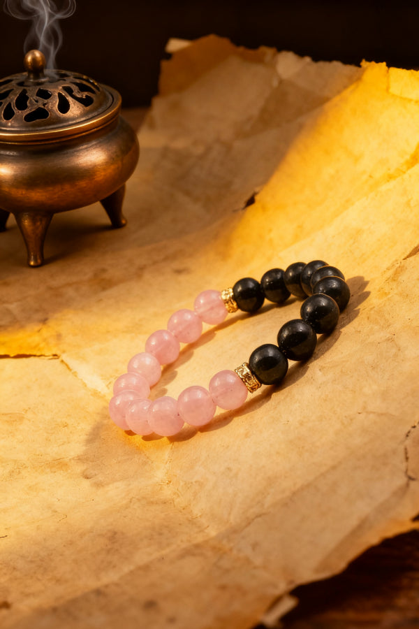 Bracelet with pink and black beads on a textured surface with an incense burner.