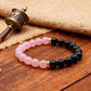 Bracelet with pink and black beads on a wooden surface with a small prayer wheel.
